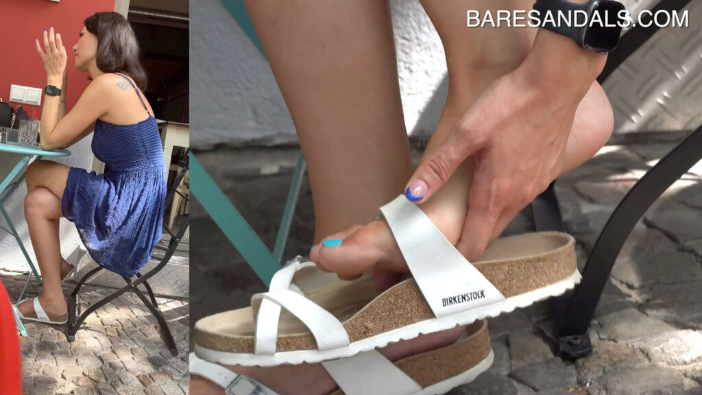 12124 – A brunette with perfect feet wearing German white sandals with blue nail polish